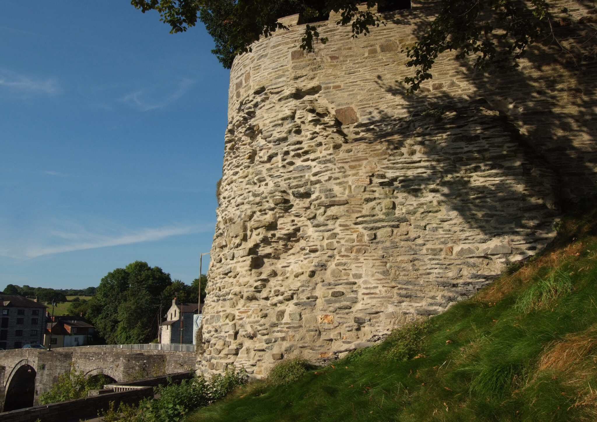 Historic Cardigan Castle walls with surrounding green landscape and stone bridge, Wales