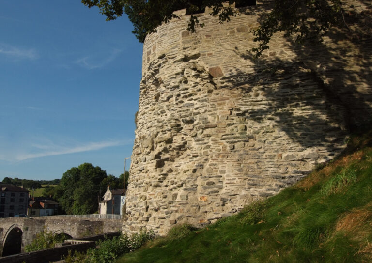 Historic Cardigan Castle walls with surrounding green landscape and stone bridge, Wales
