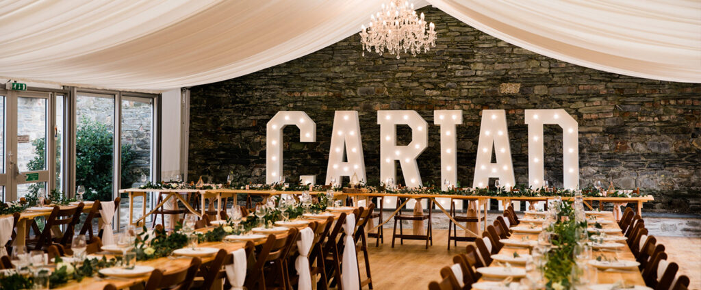 Elegant dining setup at Cardigan Castle with Cariad light-up letters and stone wall backdrop