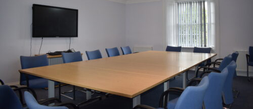 Spacious conference room at Cardigan Castle with large table and blue chairs for meetings and presentations