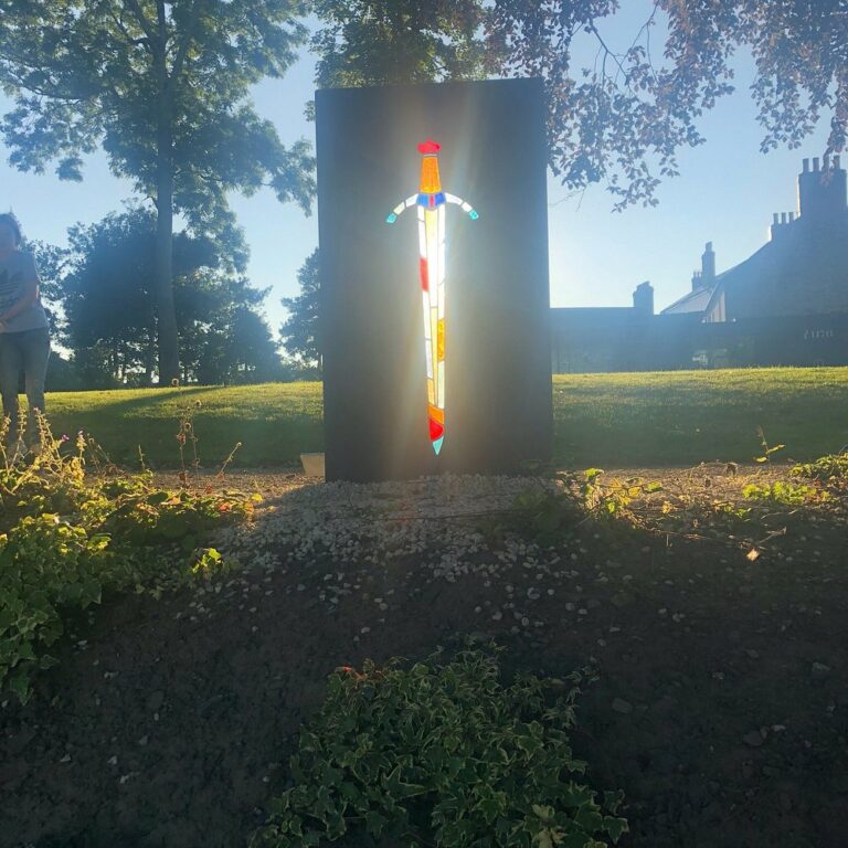 Stained-glass-inspired sculpture at Cardigan Castle illuminated by sunset light