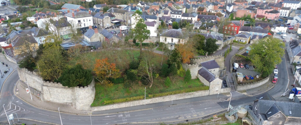 Aerial view of Cardigan Castle surrounded by vibrant autumn trees and historic town architecture.